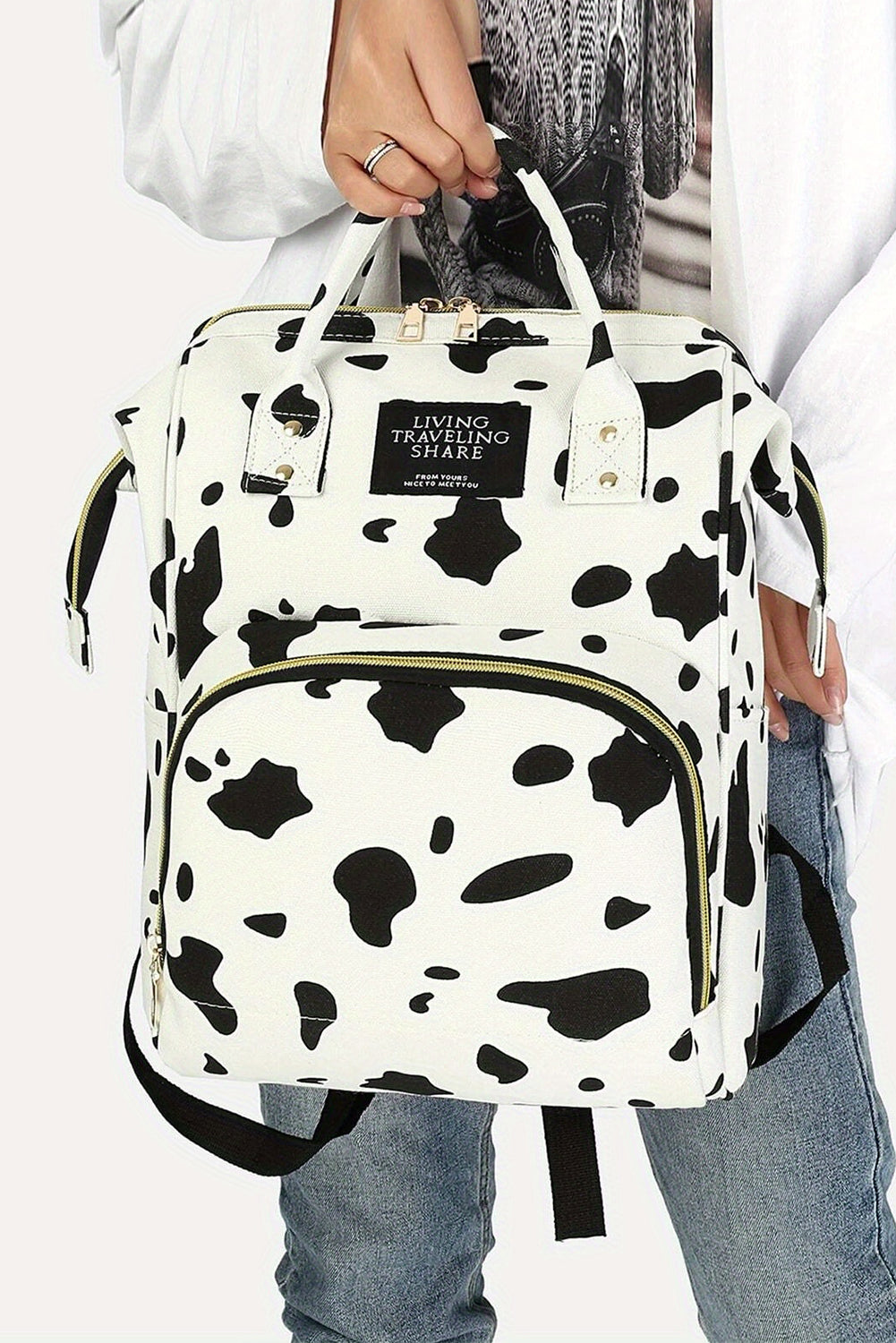 Mochila de lona con múltiples bolsillos y estampado de manchas de vaca blanca